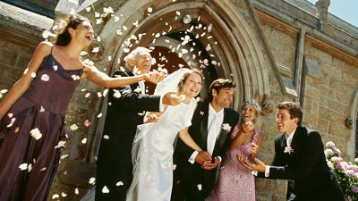 newlywed couple standing outside a church with their parents and guests